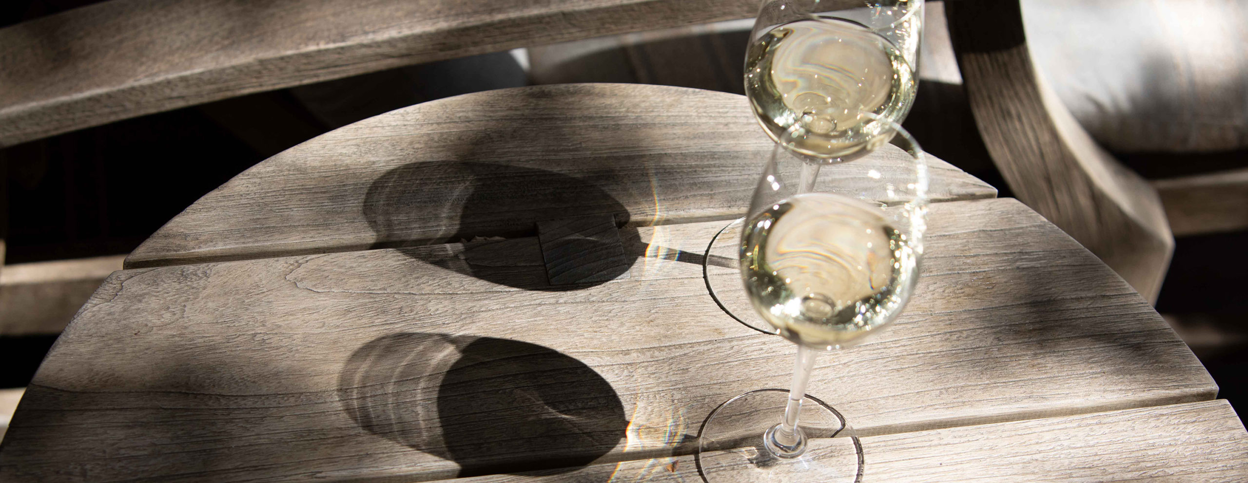 Two wine glasses on a table with shadows