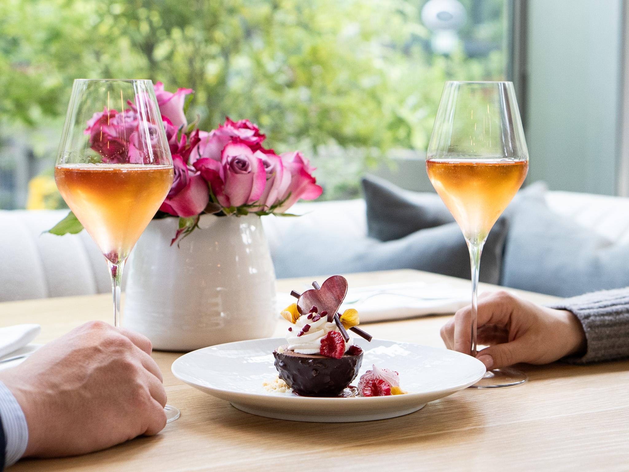 Man and woman holding glasses of sparkling wine and a chocolate dessert