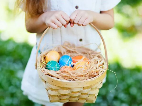 Child holding an Easter basket with colored eggs.