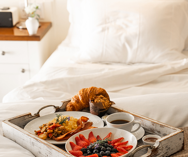 Breakfast items on a serving tray on a bed.